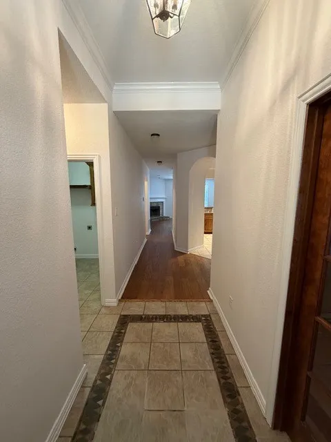 Entryway featuring a decorative tile inlay, wood-finish flooring, and crown molding