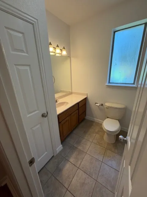 Vanity with an integrated sink, wood-finish cabinetry, and a framed mirror
