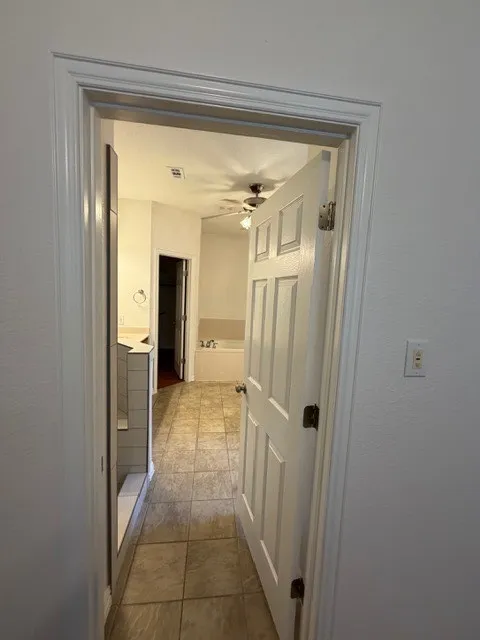 Tiled flooring, white paneled door, and ceiling fan