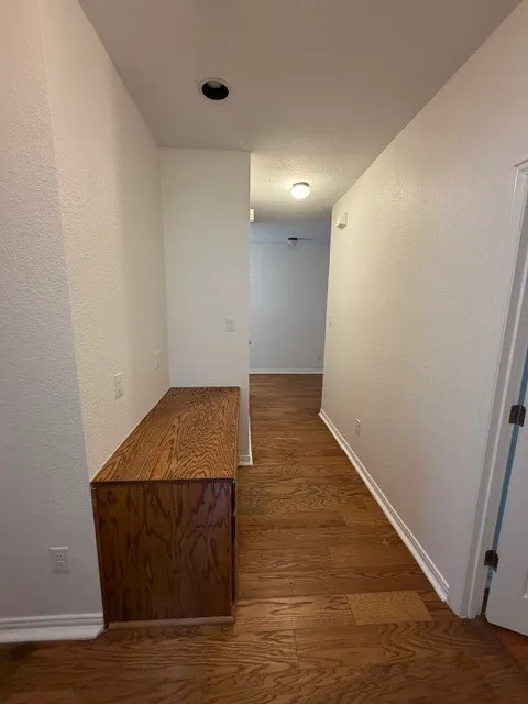Wood-finish flooring throughout, recessed ceiling lighting, and a built-in wood-finish cabinet