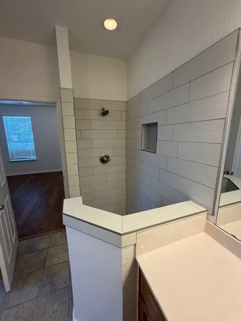 Walk-in shower with subway tile surround, recessed niche, and dark bronze fixtures