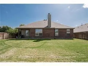 Brick exterior with a covered patio and fenced backyard