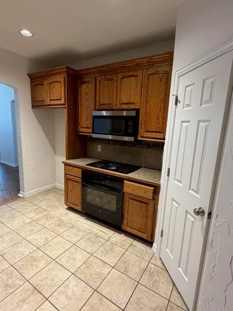 Built-in microwave, electric cooktop, and oven within wood cabinetry