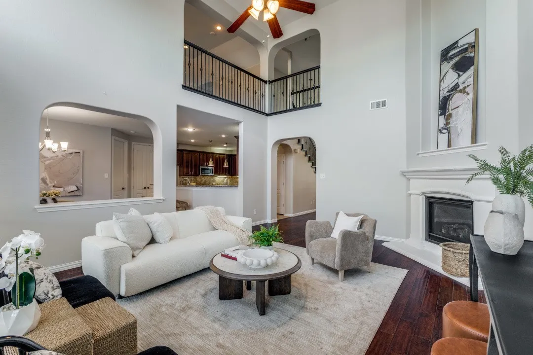 Two-story living area with high ceilings, arched doorways, a fireplace, dark wood-finish flooring, and an upper-level balcony