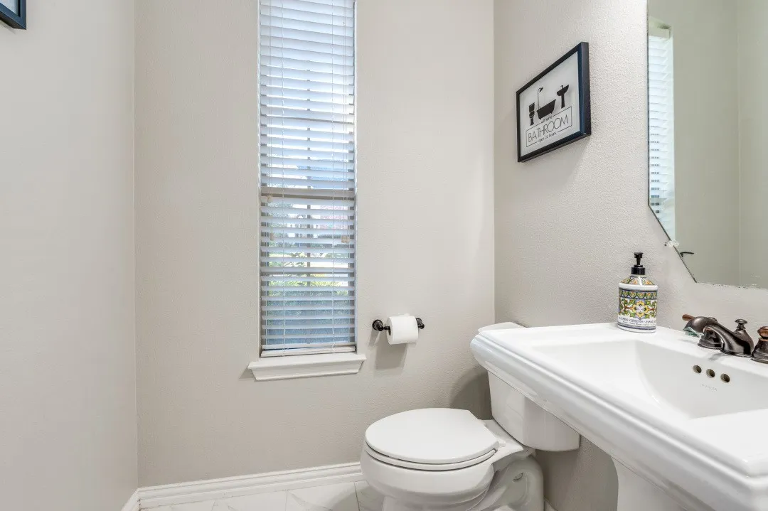 White pedestal sink with a bronze-finish faucet