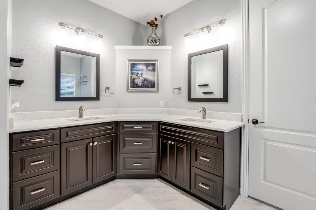 Dual vanity with dark wood-finish cabinetry, white countertops, undermount sinks, and brushed nickel fixtures
