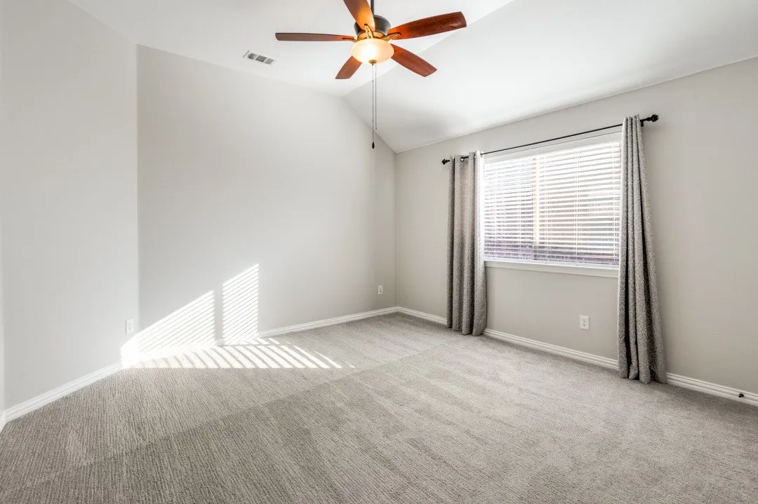 Interior room featuring vaulted ceilings, a ceiling fan, a window with blinds, and light-toned carpeting