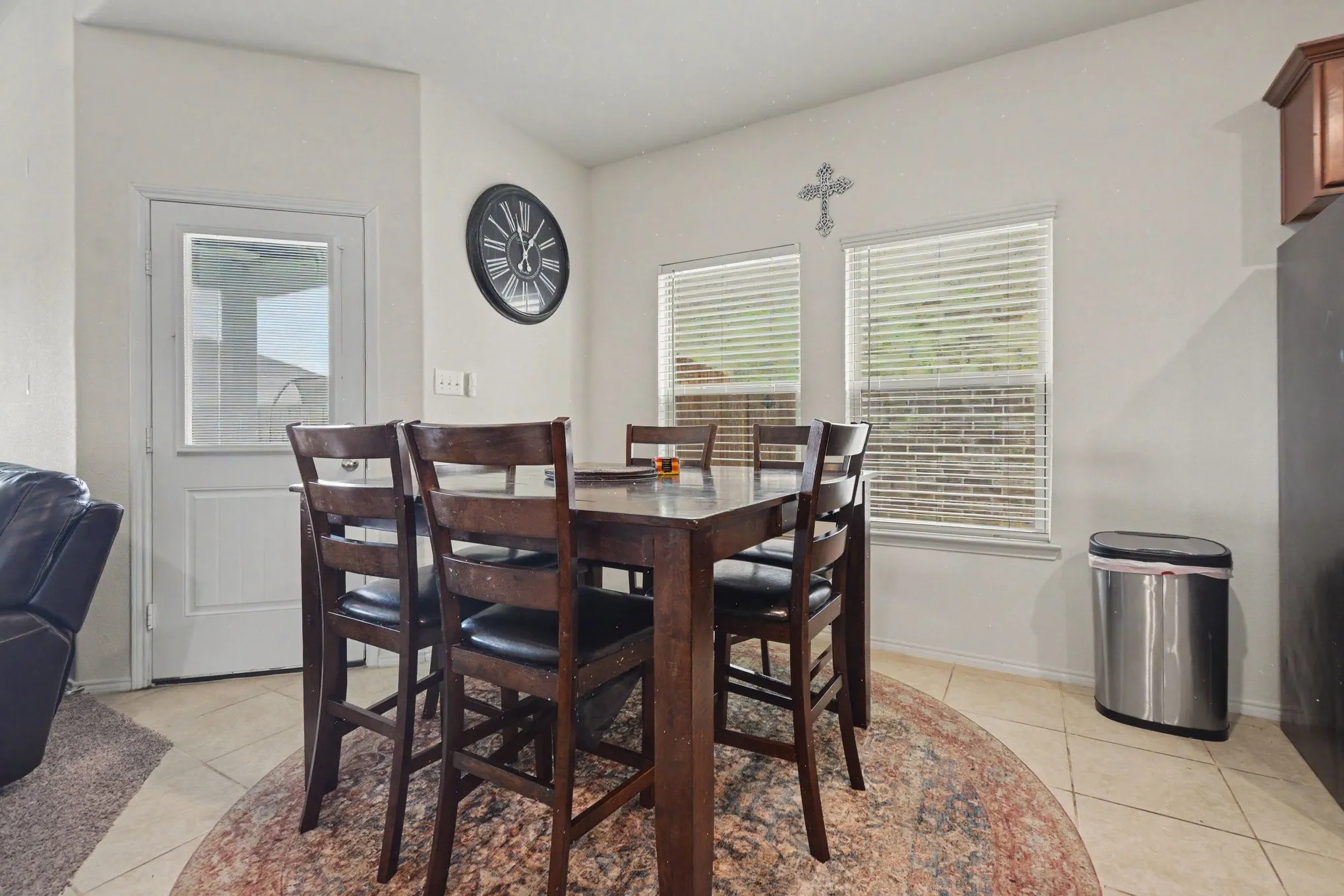 Dining area featuring tile flooring, a white paneled door with a glass insert, and two windows with blinds
