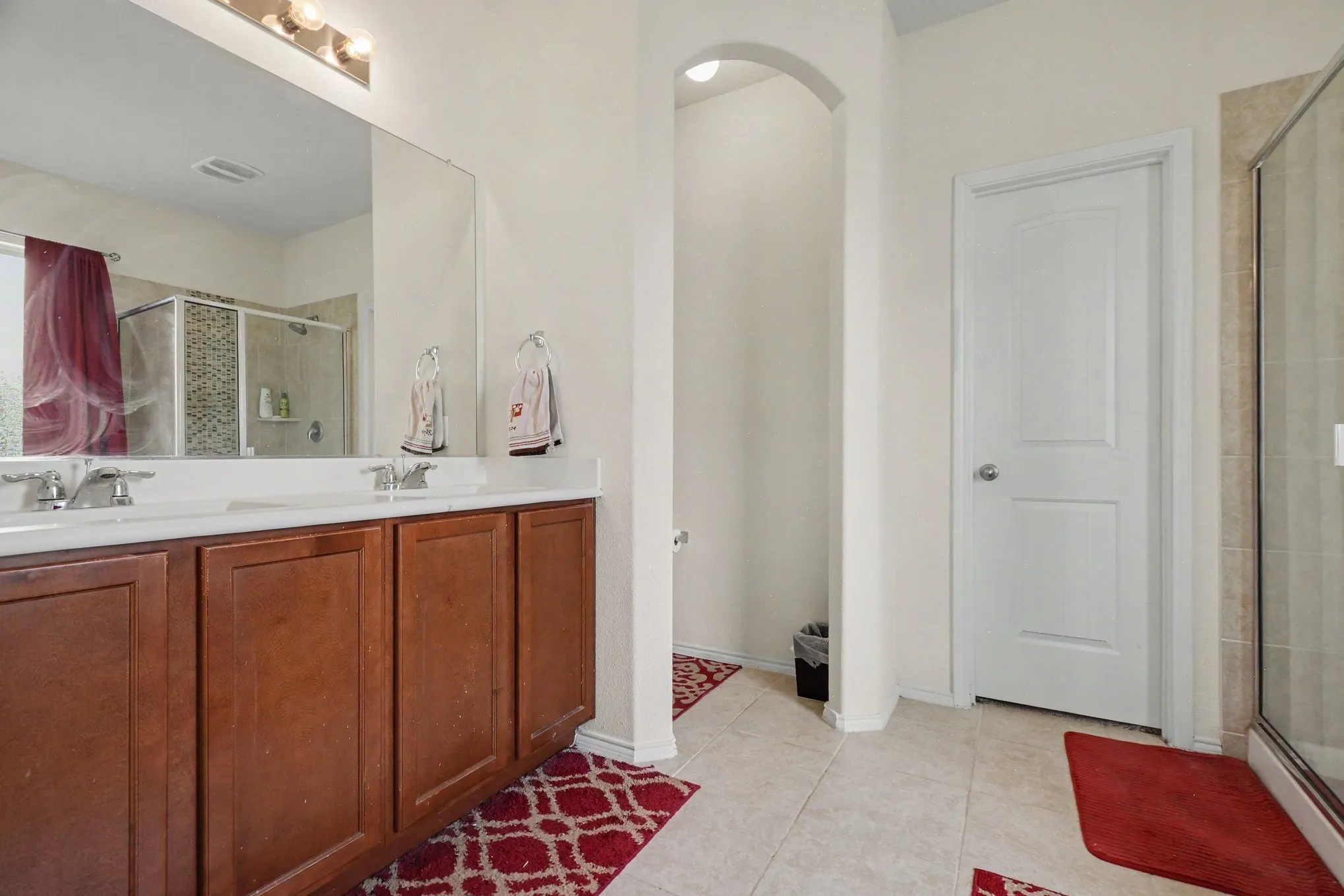 Double vanity with wood-finish cabinetry, a large mirror, and overhead lighting