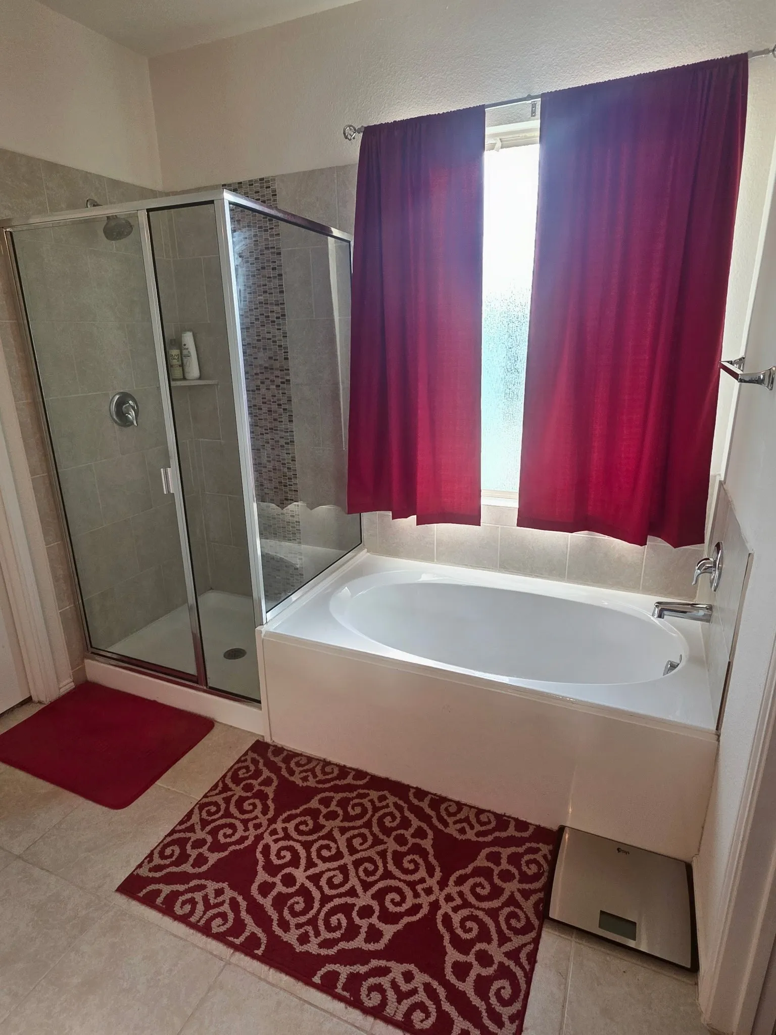 Full bathroom featuring a built-in soaking tub, a separate glass-enclosed shower with tiled walls, and light-toned floor tiling