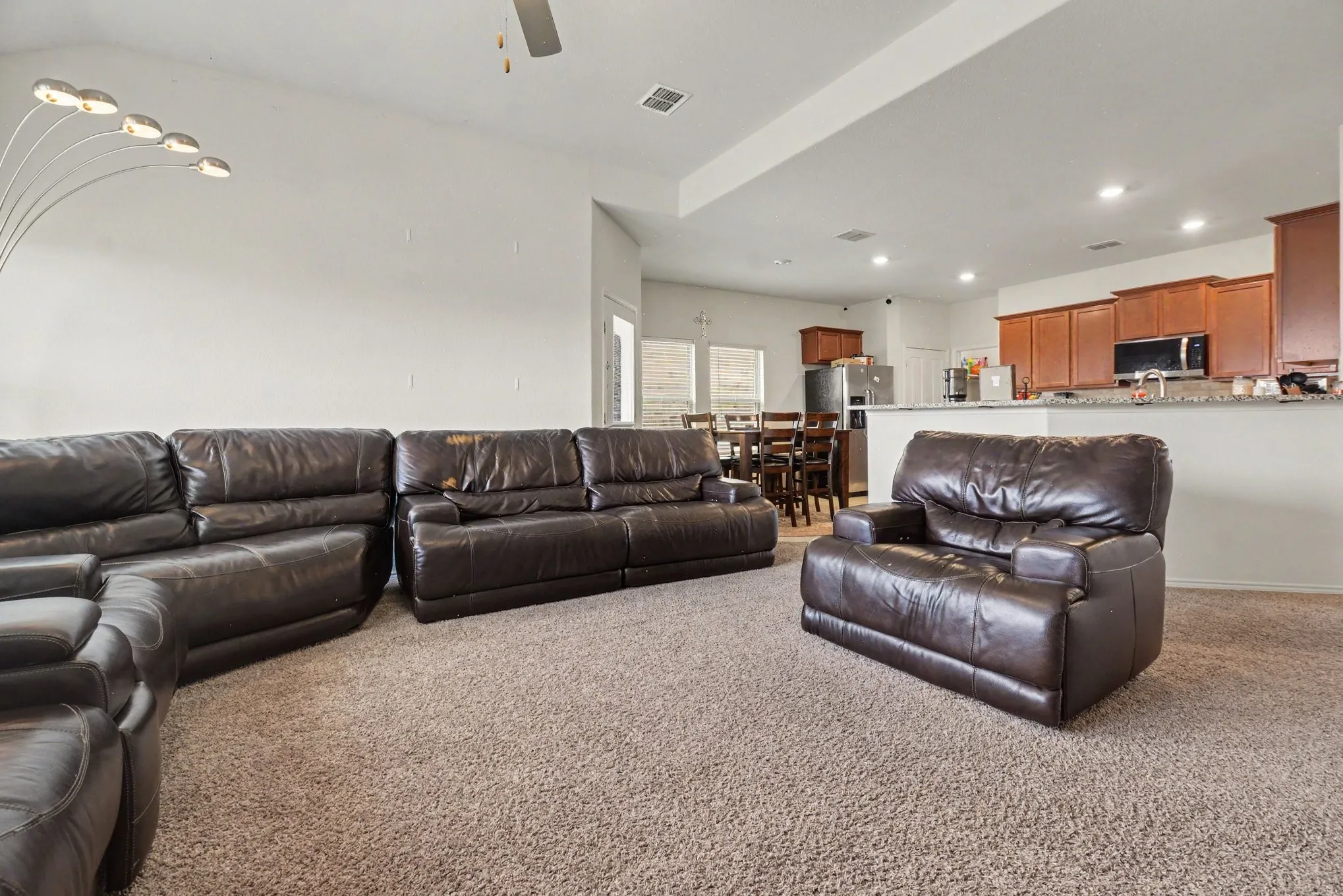 Open-concept living area with carpet flooring, a vaulted ceiling, and recessed lighting