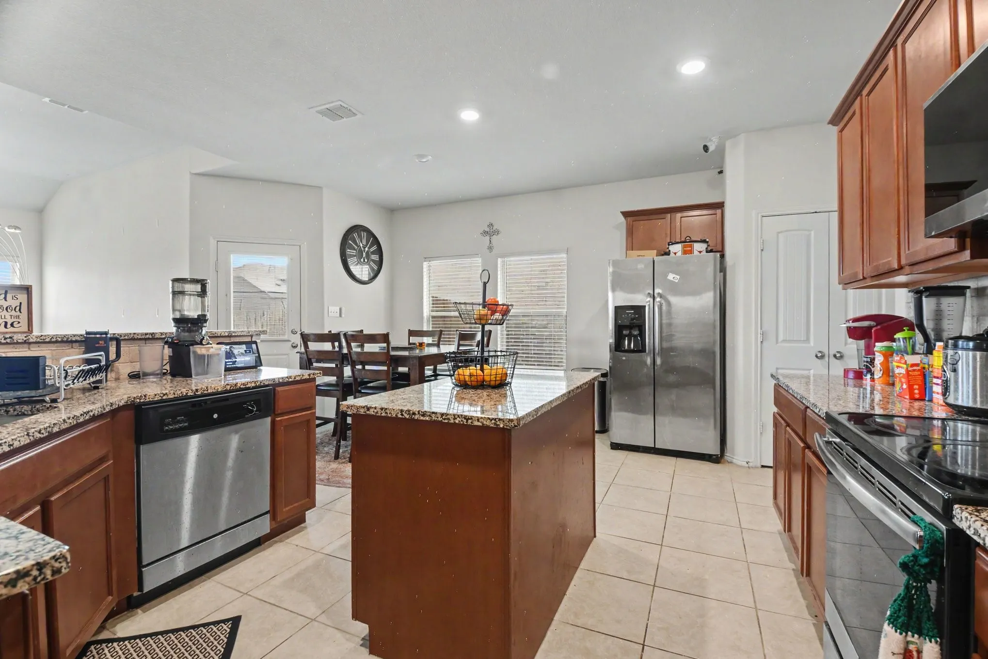 Open-concept kitchen featuring granite countertops, wood cabinetry, stainless steel appliances, and tile​​‌​​​​‌​​‌‌​‌‌​​​‌‌​‌​‌​‌​​​‌​​ flooring