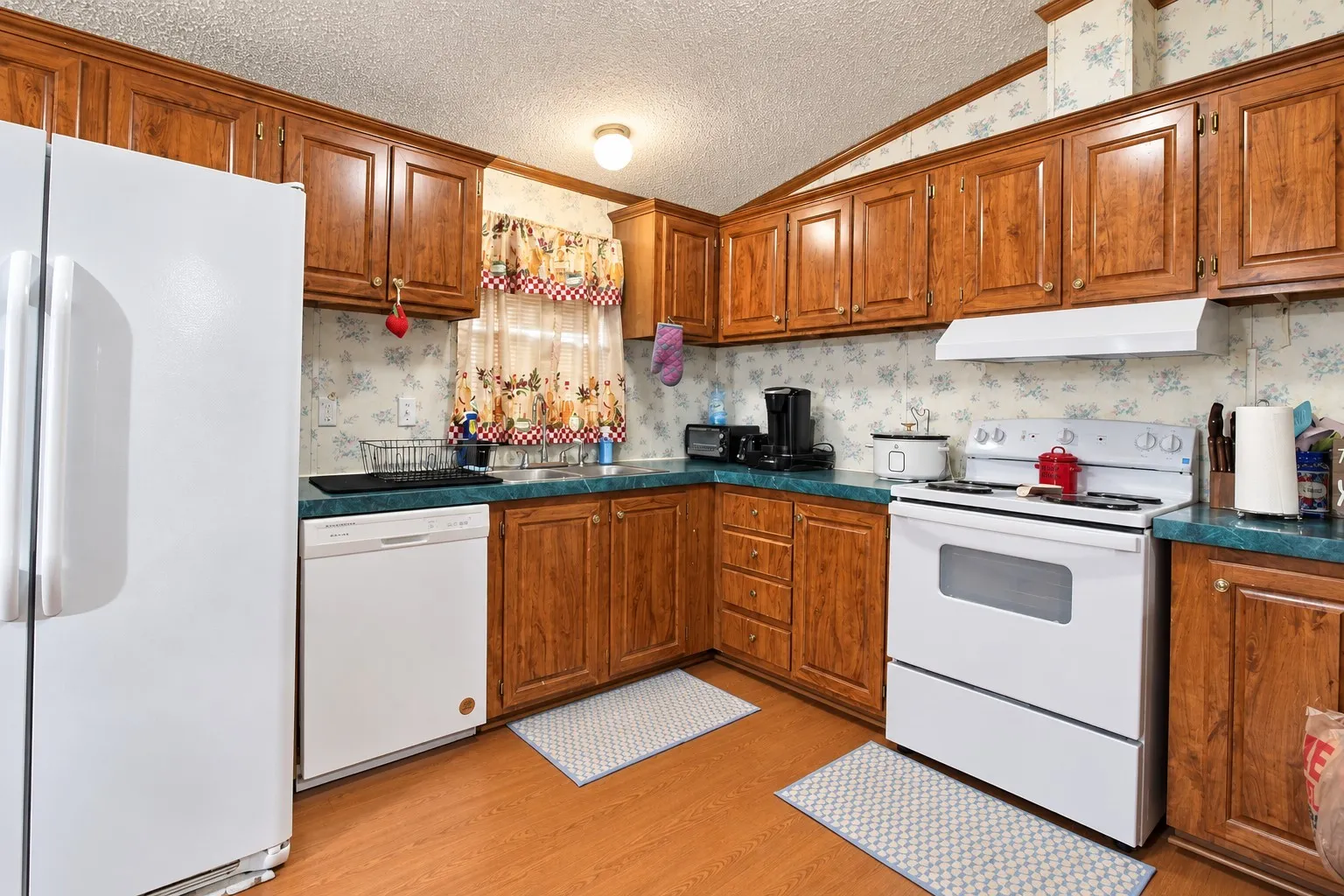 Wood-finish cabinetry, white appliances, and laminate countertops