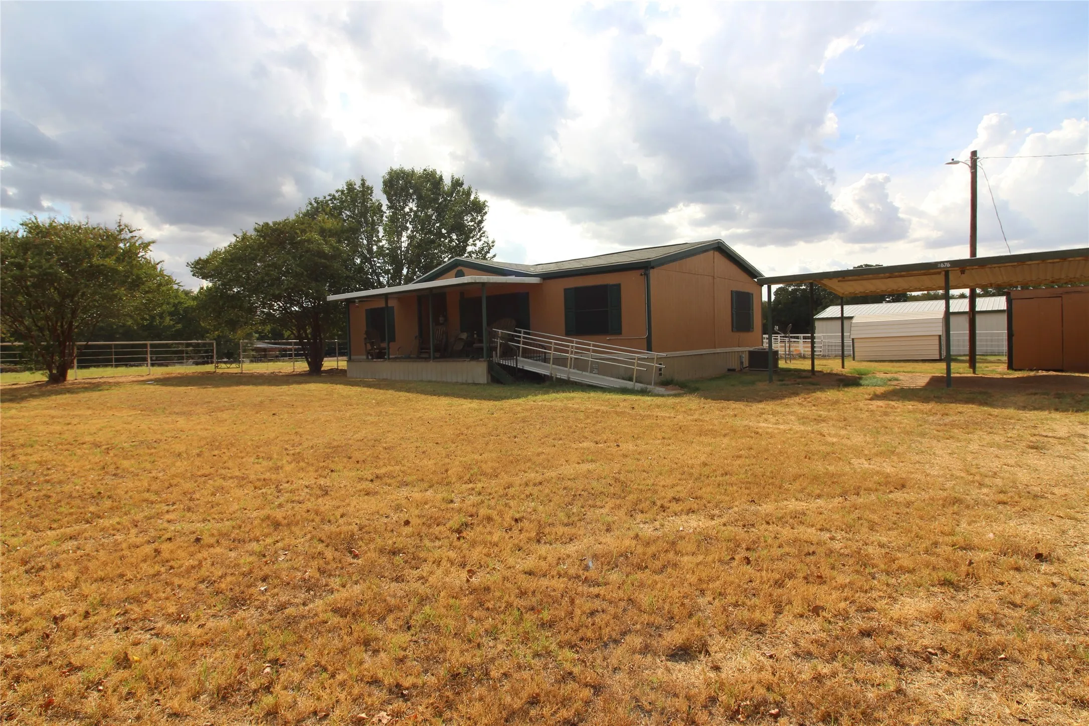 Expansive outdoor area featuring a single-story residence, covered front porch, and a dedicated ramp entrance