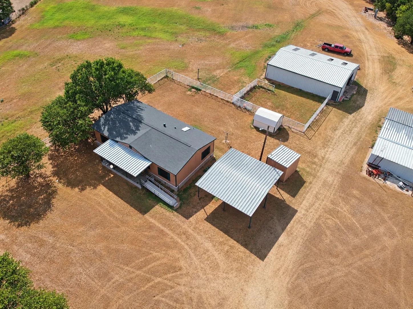 Expansive property featuring a single-story residence, multiple outbuildings, a covered carport, and fenced areas