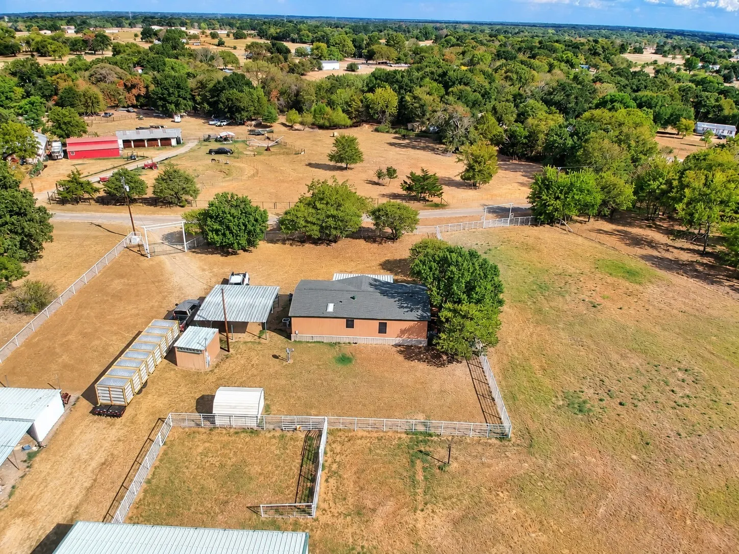 Expansive property featuring multiple structures, open fields, and mature trees