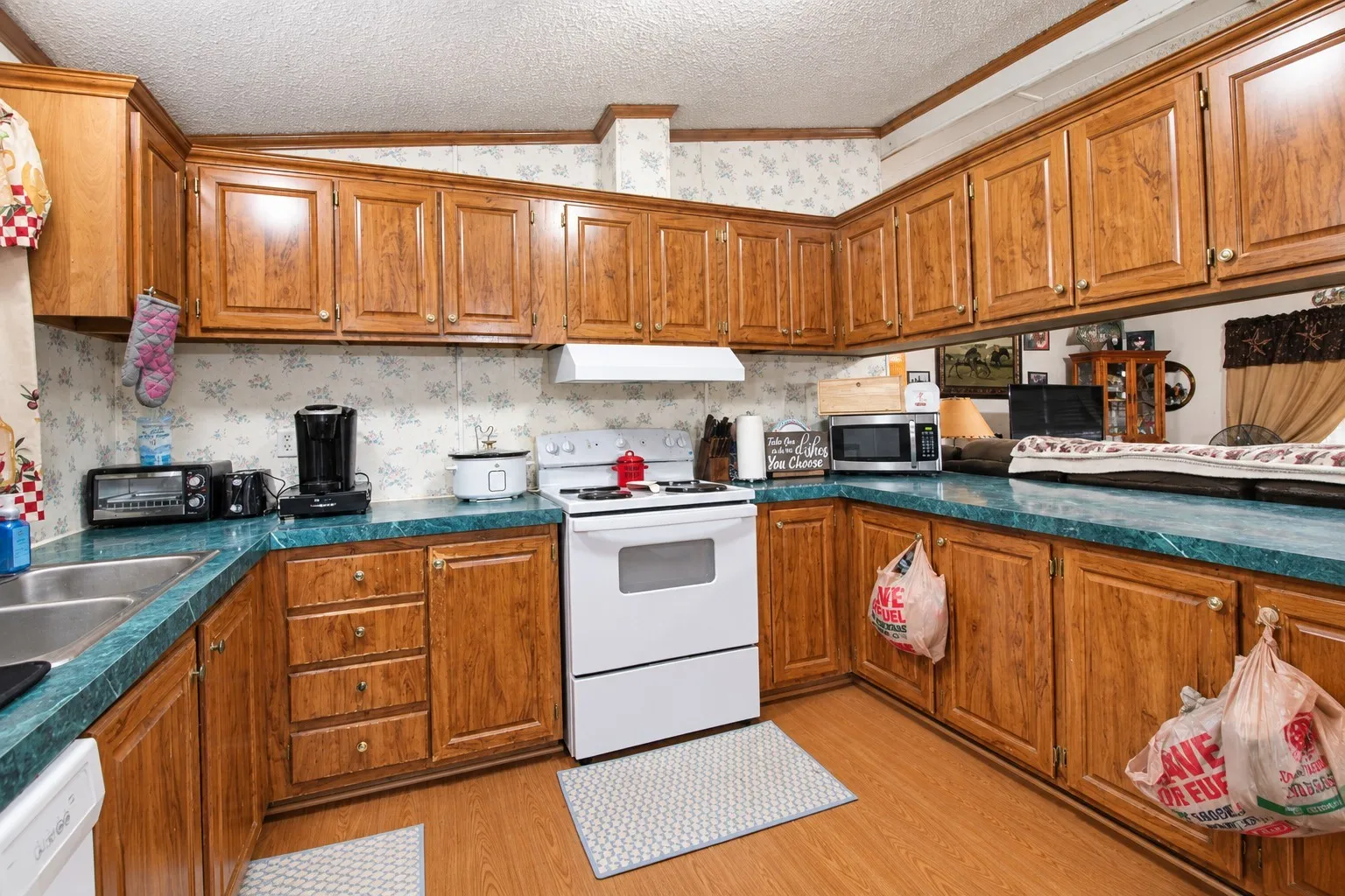 U-shaped kitchen with wood-finish cabinetry, green countertops, and a white oven/range
