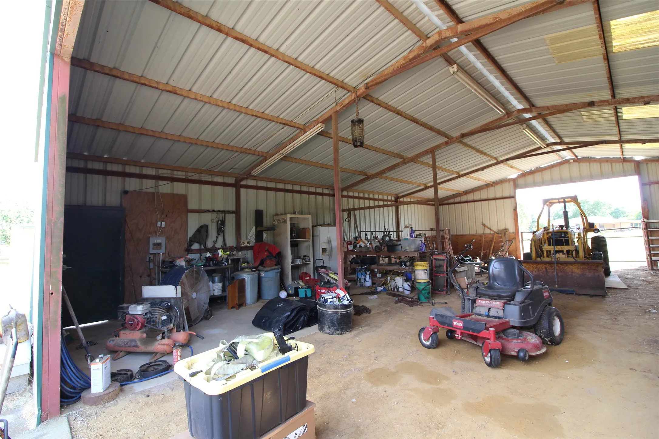 Metal-framed outbuilding with a corrugated metal roof, corrugated metal siding, and a gravel floor