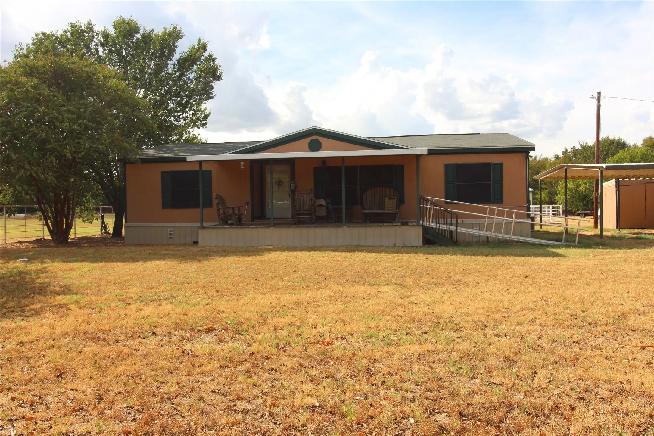Single-story residence featuring a covered front porch, an accessible ramp, and a detached carport