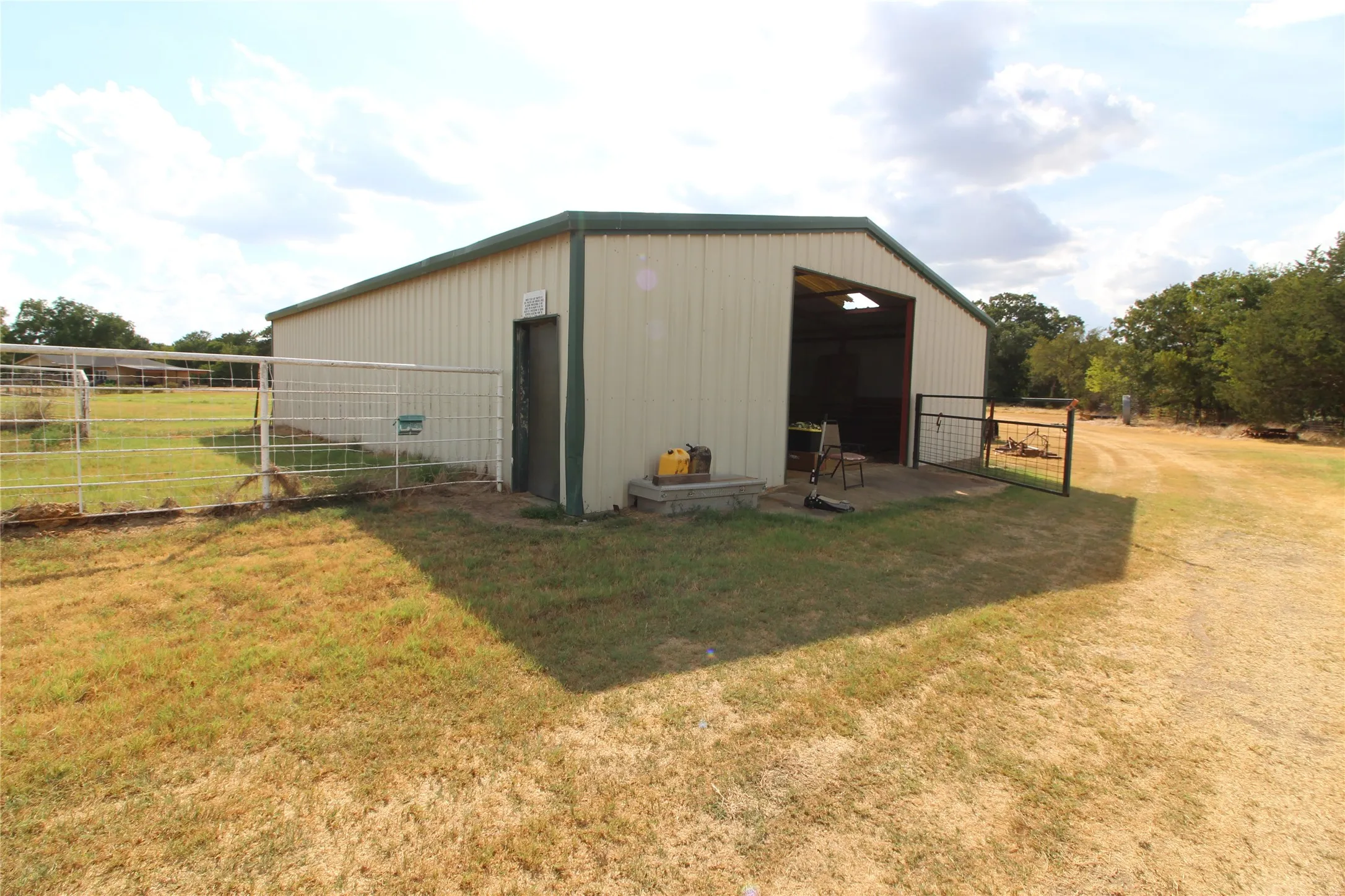 Metal-sided barn structure with a green trim roof and a large open bay entrance