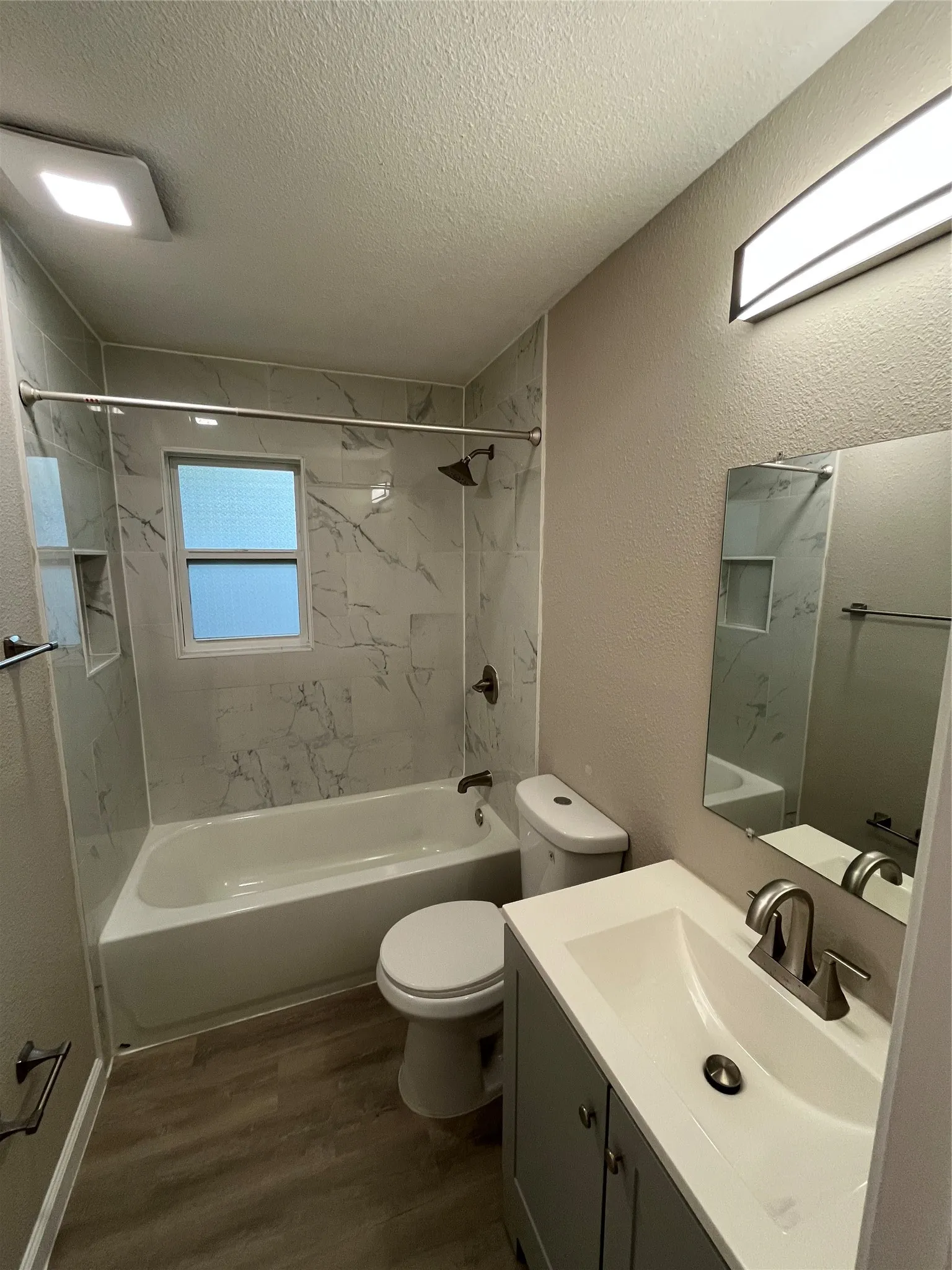 Tub and shower combination with marble-look tile surround and built-in niche
