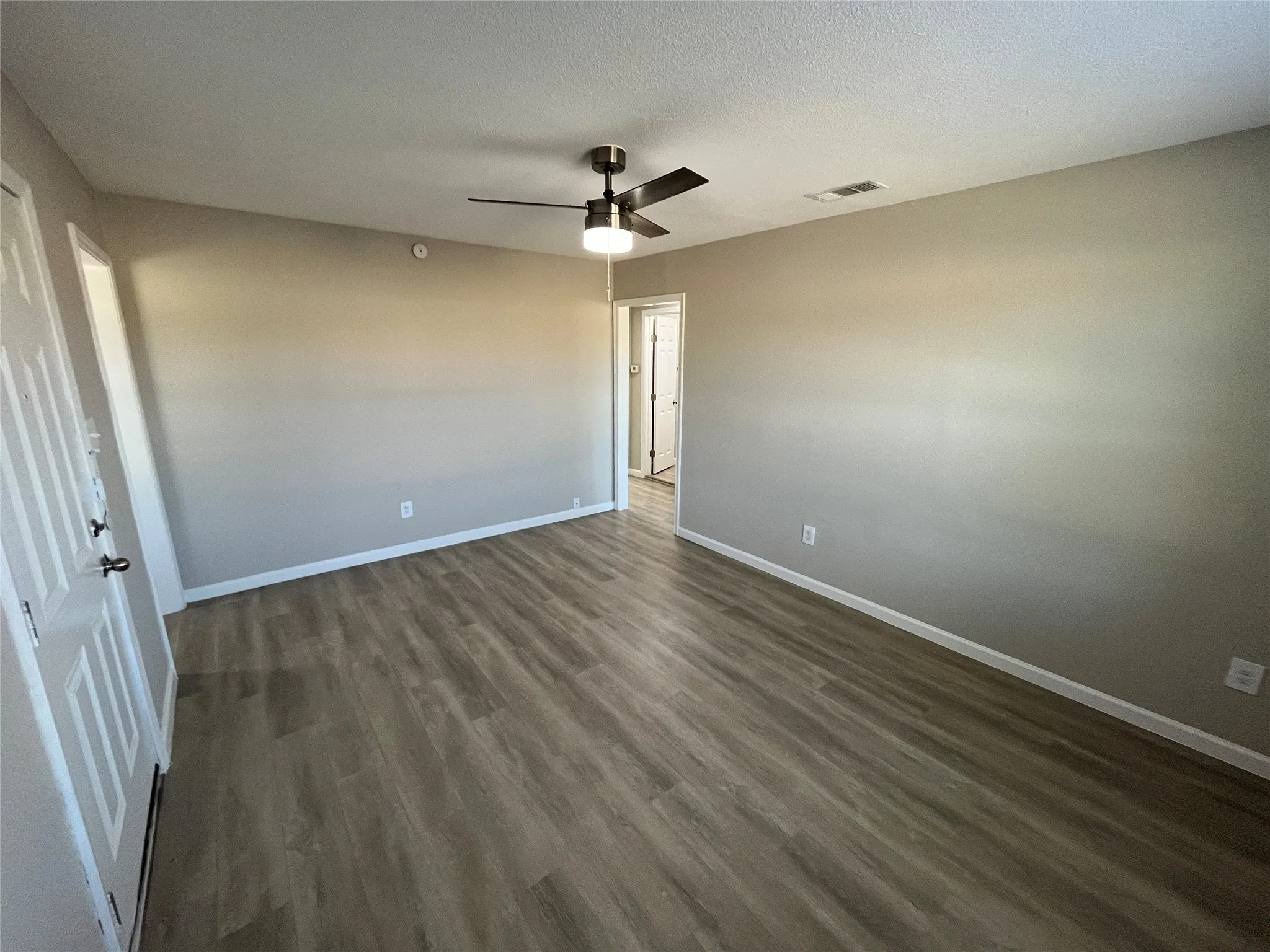 Wood-finish flooring, ceiling fan with integrated lighting, and neutral wall tones