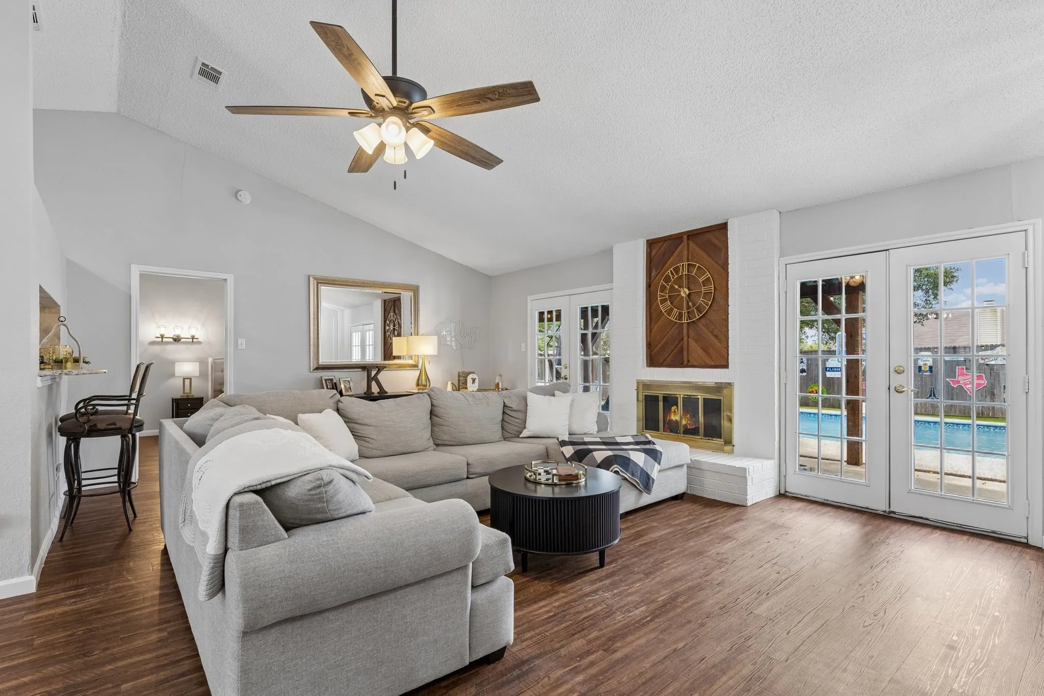 Living room with fresh paint, tall ceilings, vinyl flooring, wood burning fireplace, and 2 exits leading to back yard