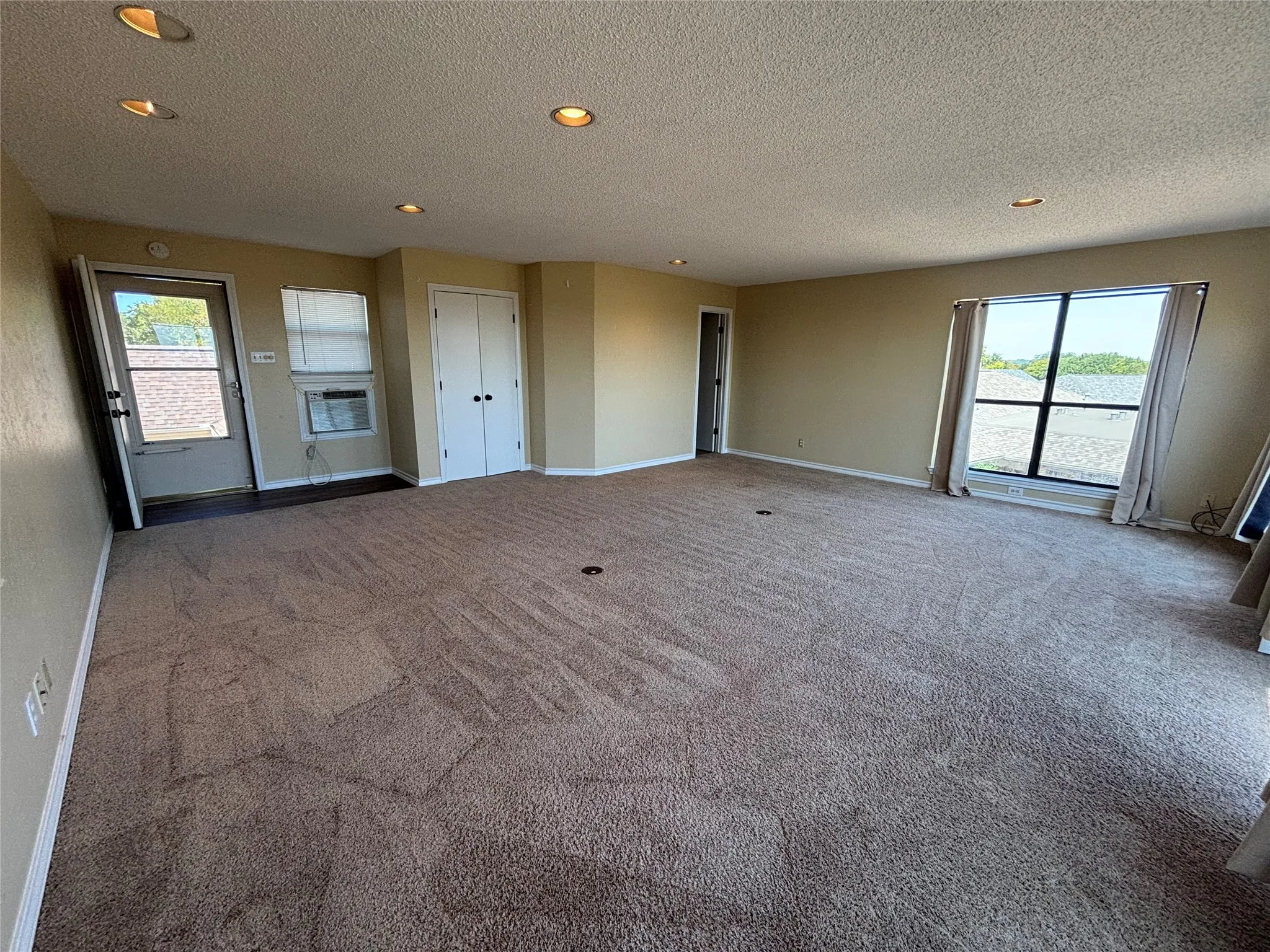 Expansive room with carpet flooring, recessed lighting, double-door closet, and large window