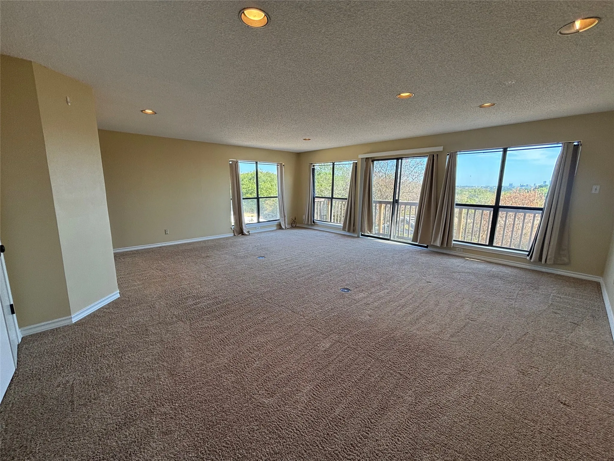 Expansive room with neutral carpeting, recessed ceiling lighting, and multiple windows providing ample natural light