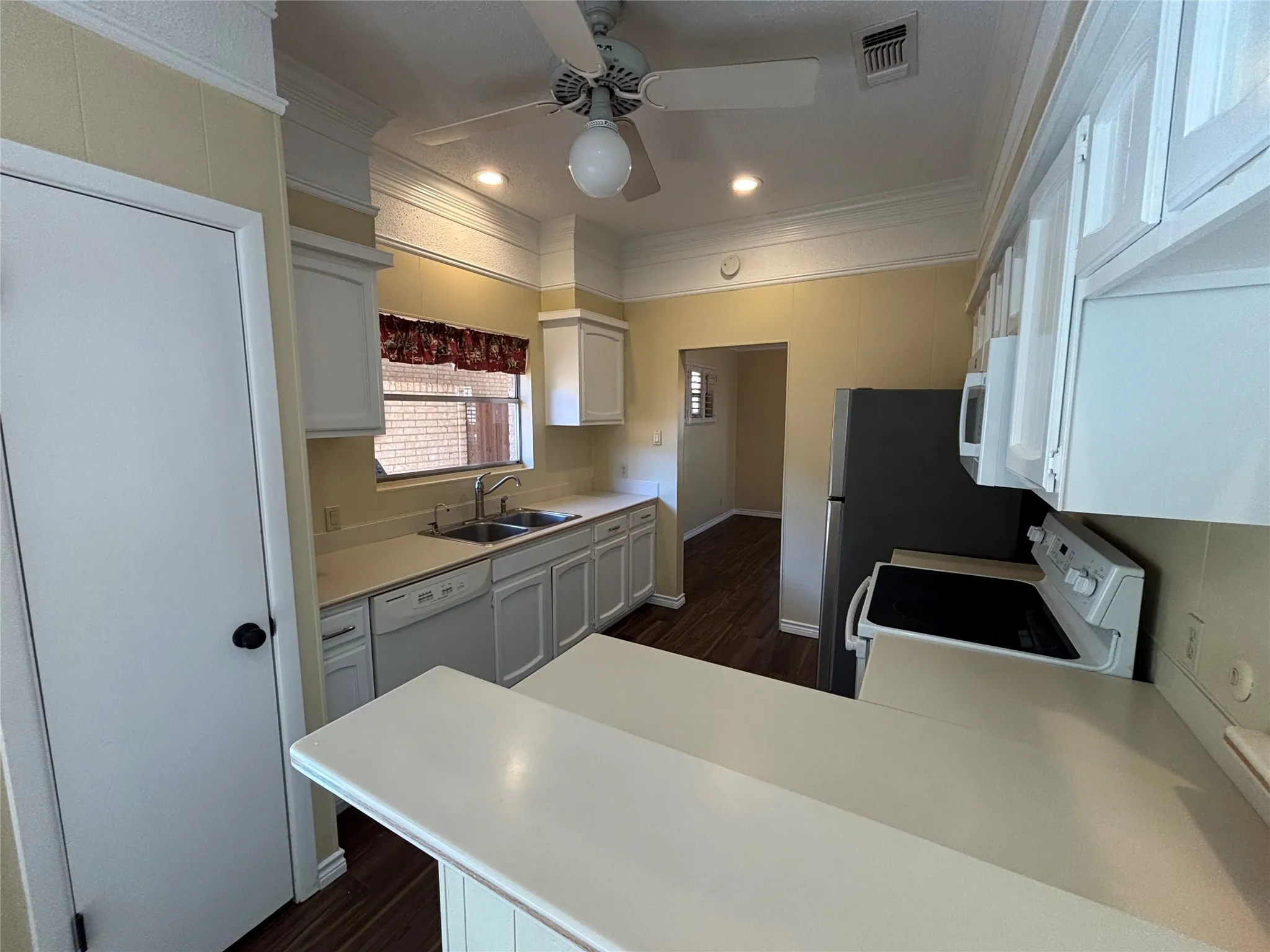 Kitchen featuring white cabinetry, light-toned countertops, a ceiling fan, and wood-finish flooring