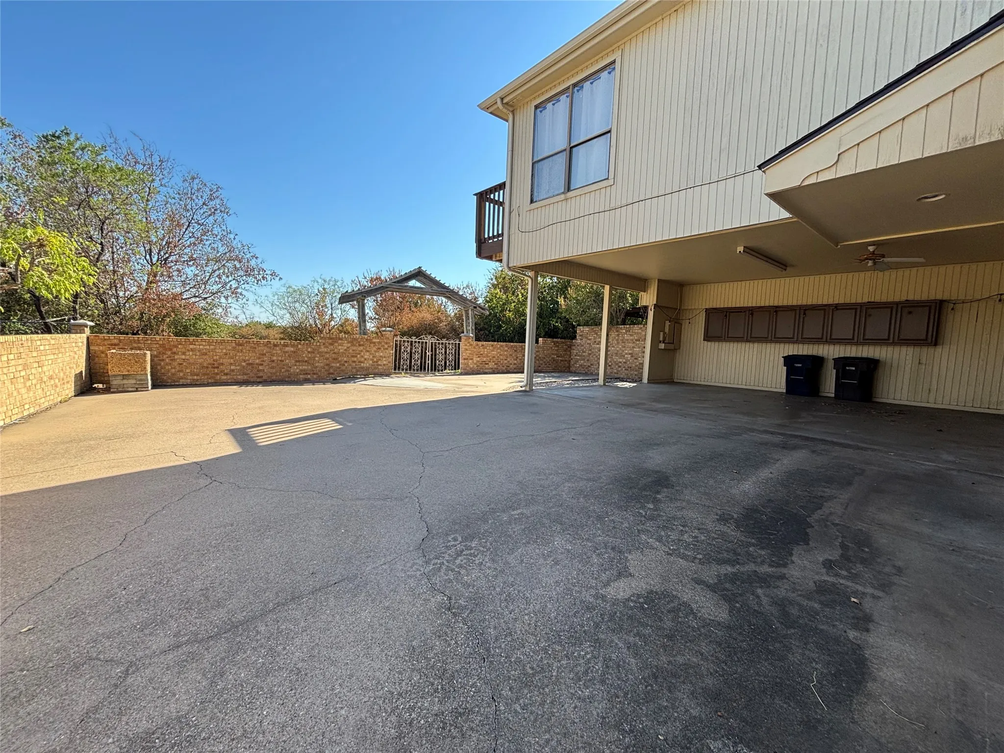 Expansive paved driveway leading to a covered parking area with built-in cabinetry
