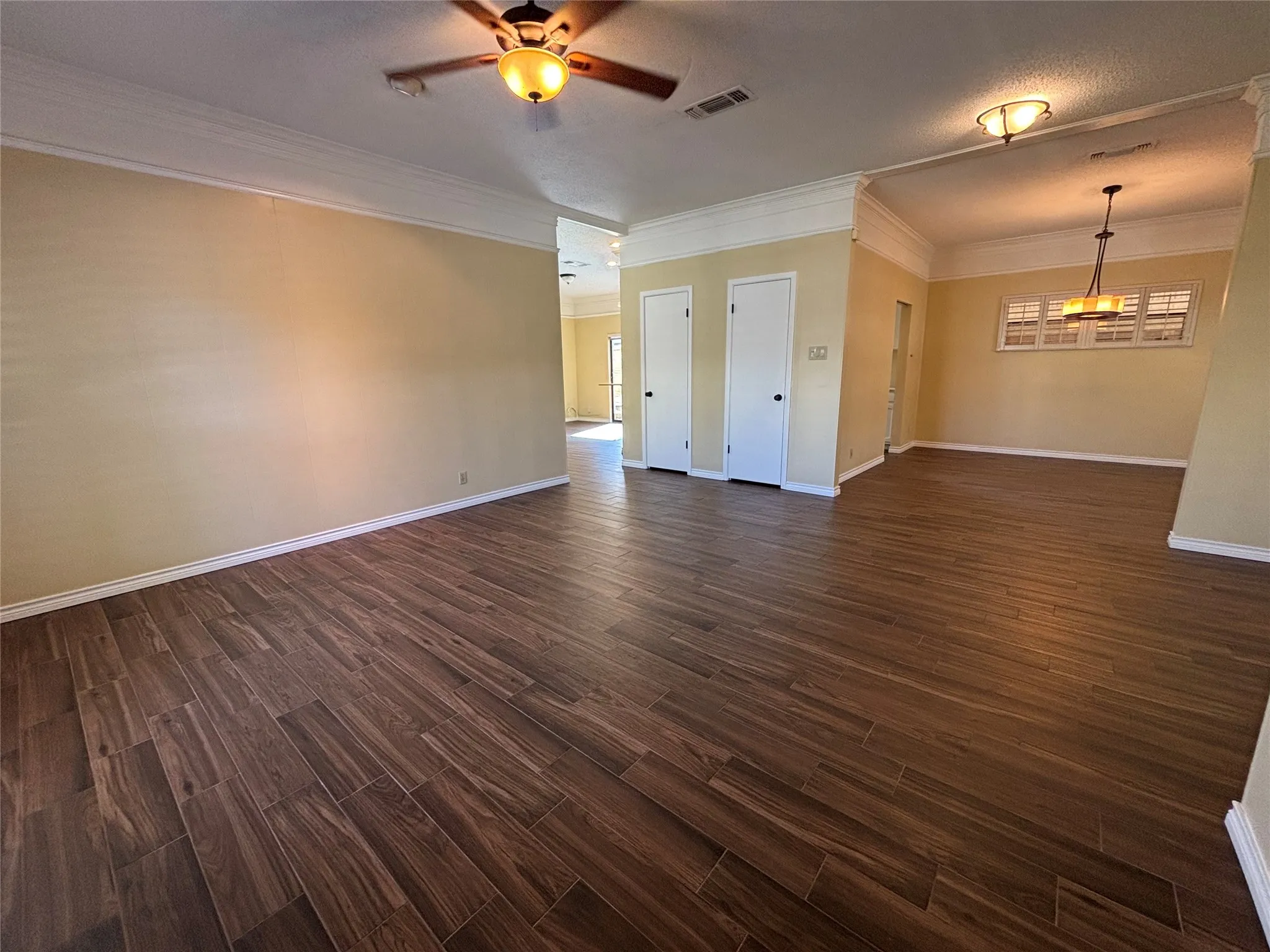 Wood-finish tile flooring throughout, crown molding details, white trim, and a ceiling fan with integrated lighting