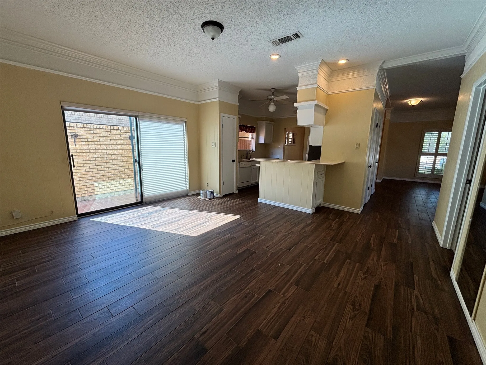 Wood-finish flooring throughout, crown molding, sliding glass door with blinds, breakfast bar, and recessed lighting