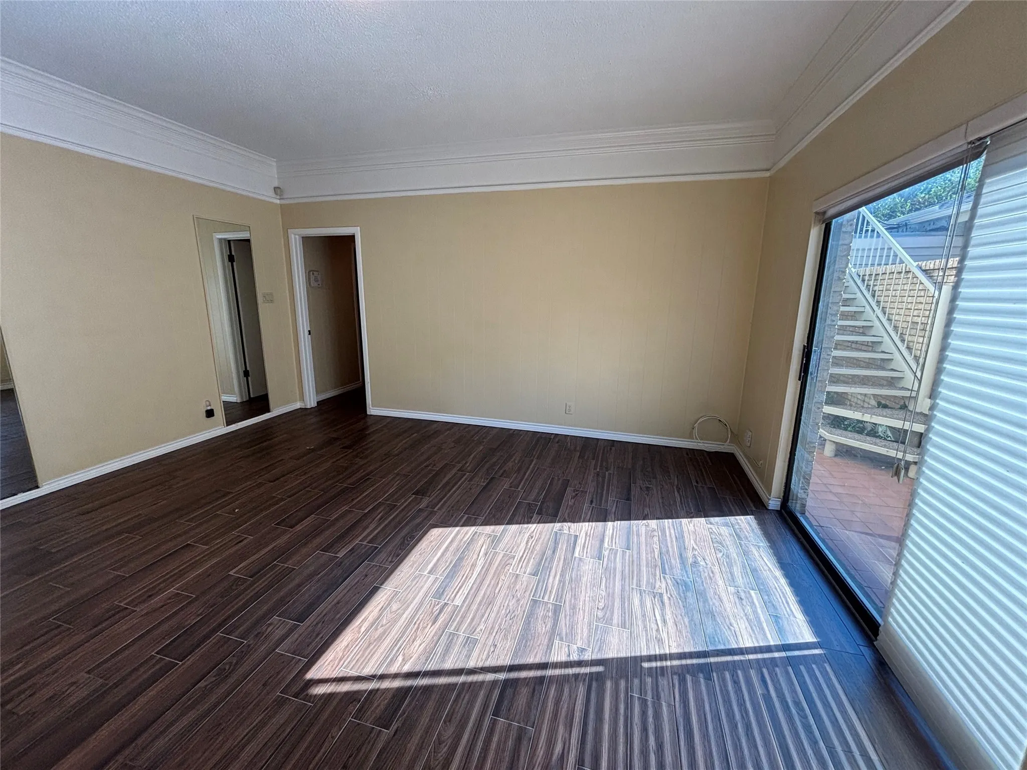 Wood-finish flooring, crown molding, and a sliding glass door