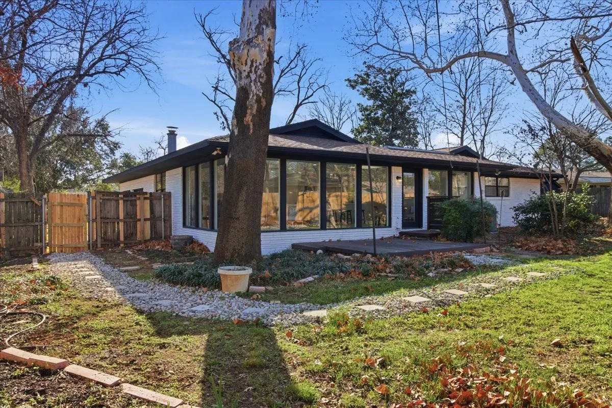 Single-story residence featuring a white brick exterior, dark window frames, and a dark roof