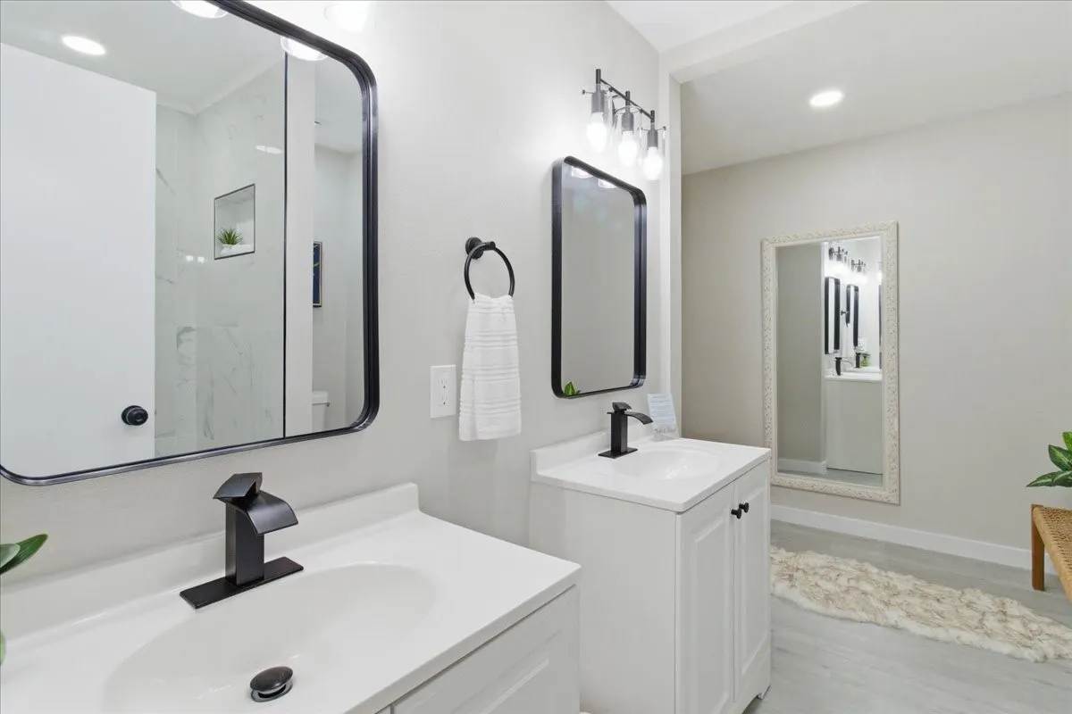 Dual vanities with white cabinetry, black framed mirrors, and black modern faucets