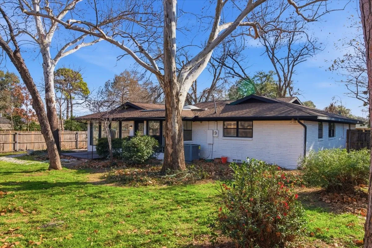White brick exterior with dark trim and a dark shingle roof