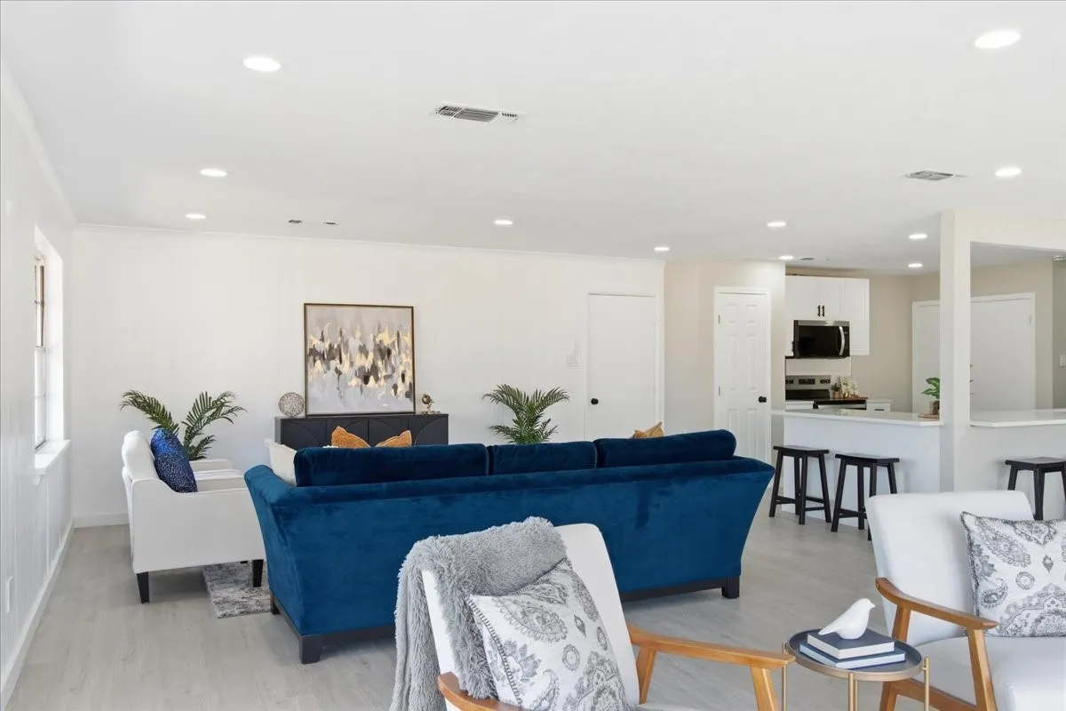 Open-concept living area featuring wood-finish flooring, recessed lighting, and crown molding