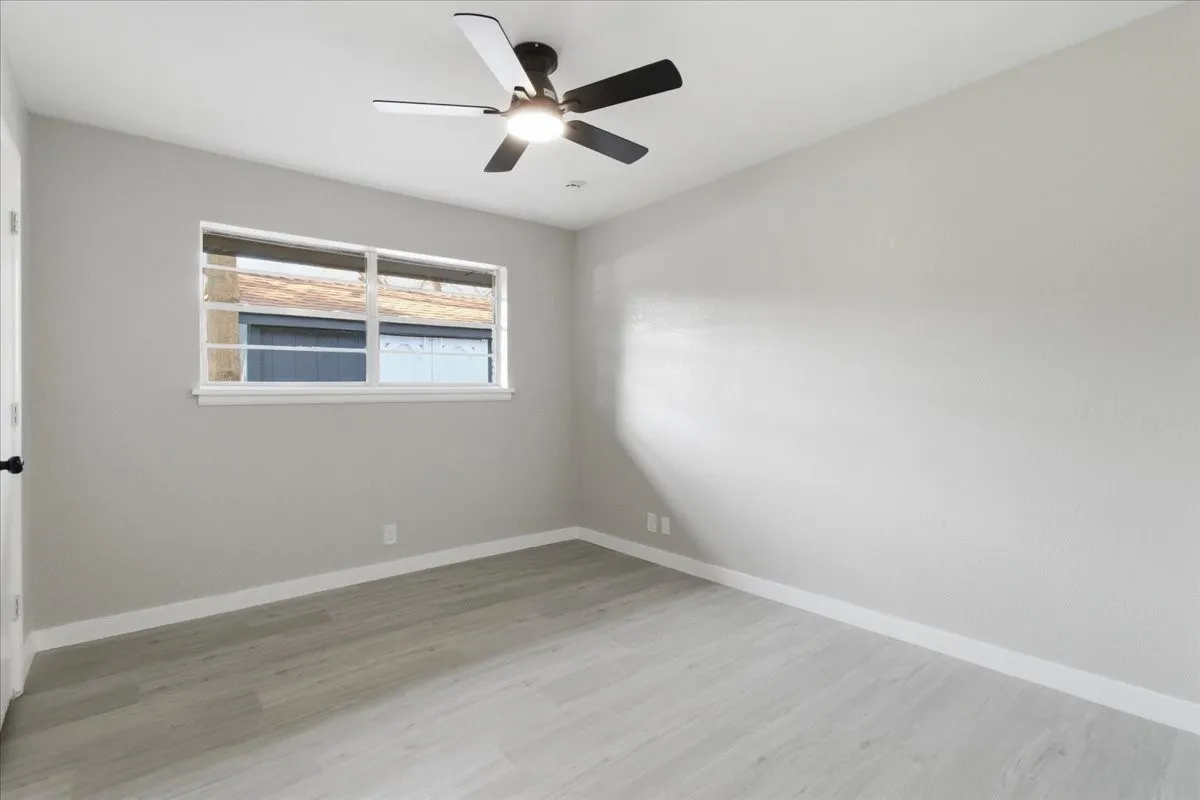 Light-toned wood-finish flooring, neutral wall tones, and a modern ceiling fan with integrated lighting