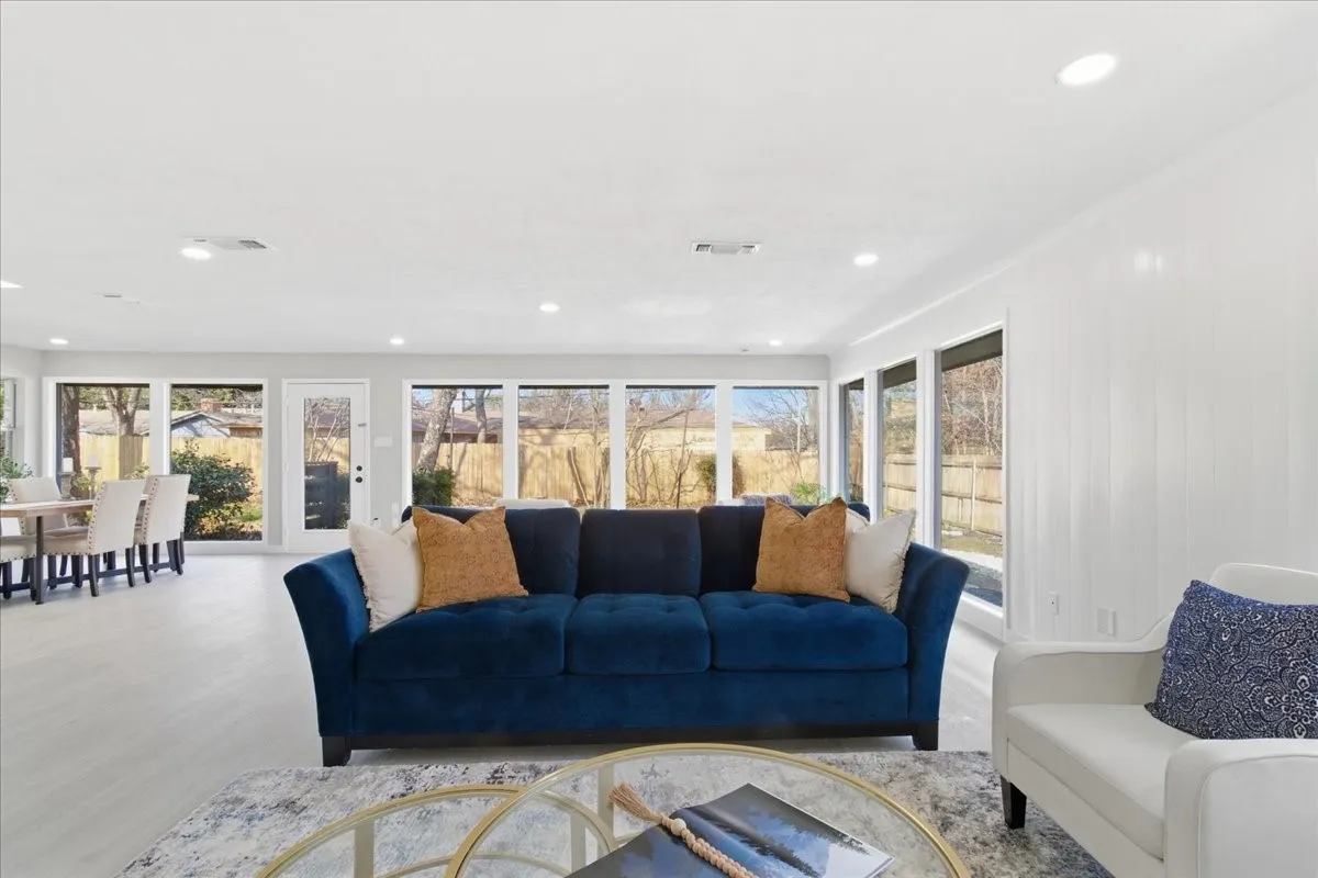 Open-concept living space with light wood-finish flooring, recessed lighting, and expansive windows