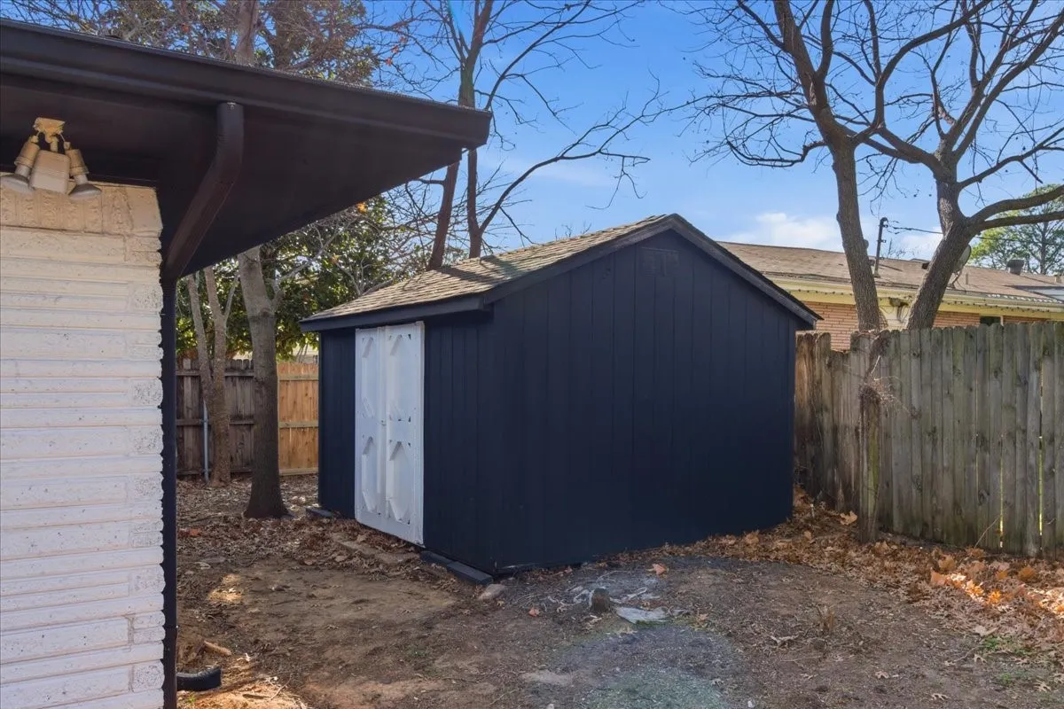 Detached storage shed with dark vertical siding and a shingled roof