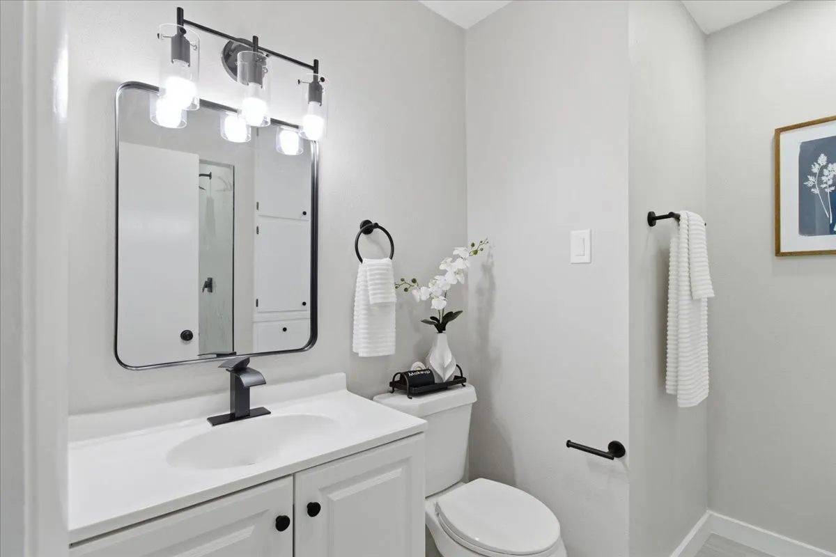 White vanity with integrated sink and matte black faucet, framed mirror, and coordinating matte black light fixture