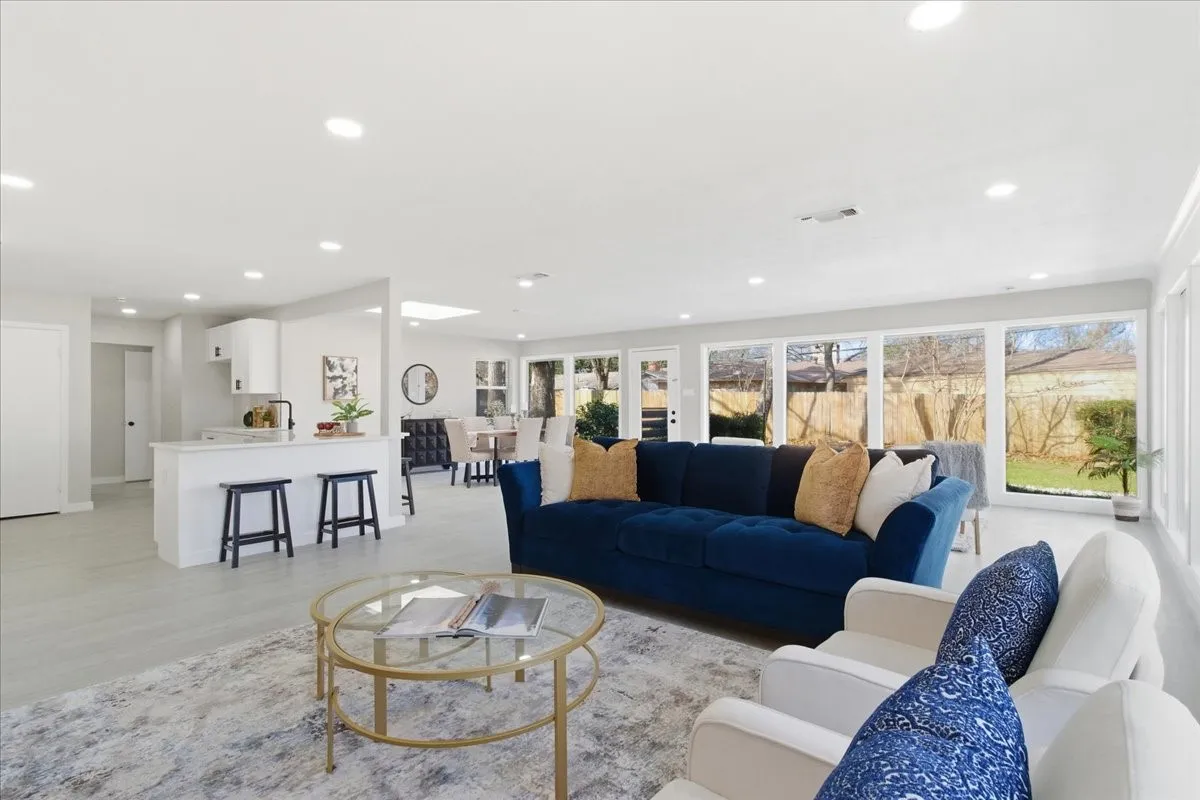 Open-concept living area featuring light-toned flooring, recessed lighting, expansive windows, a kitchen with a peninsula, and a dining area
