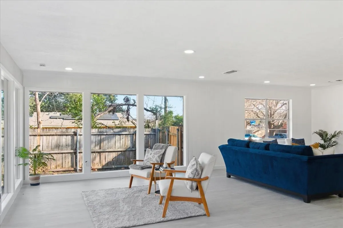Spacious room featuring light-toned flooring, white walls, recessed ceiling lighting, and large windows