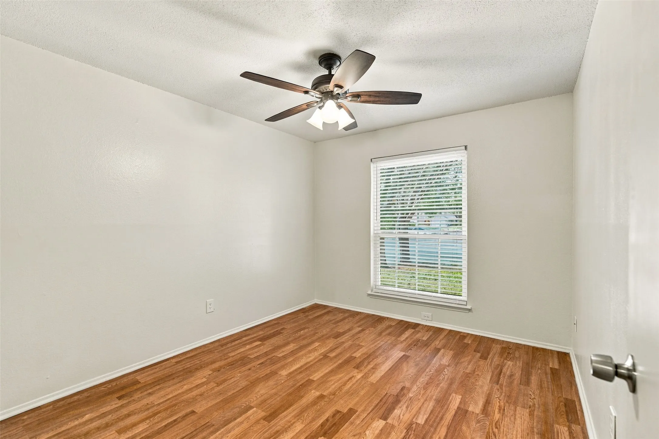 Wood-finish flooring, ceiling fan, and window with blinds