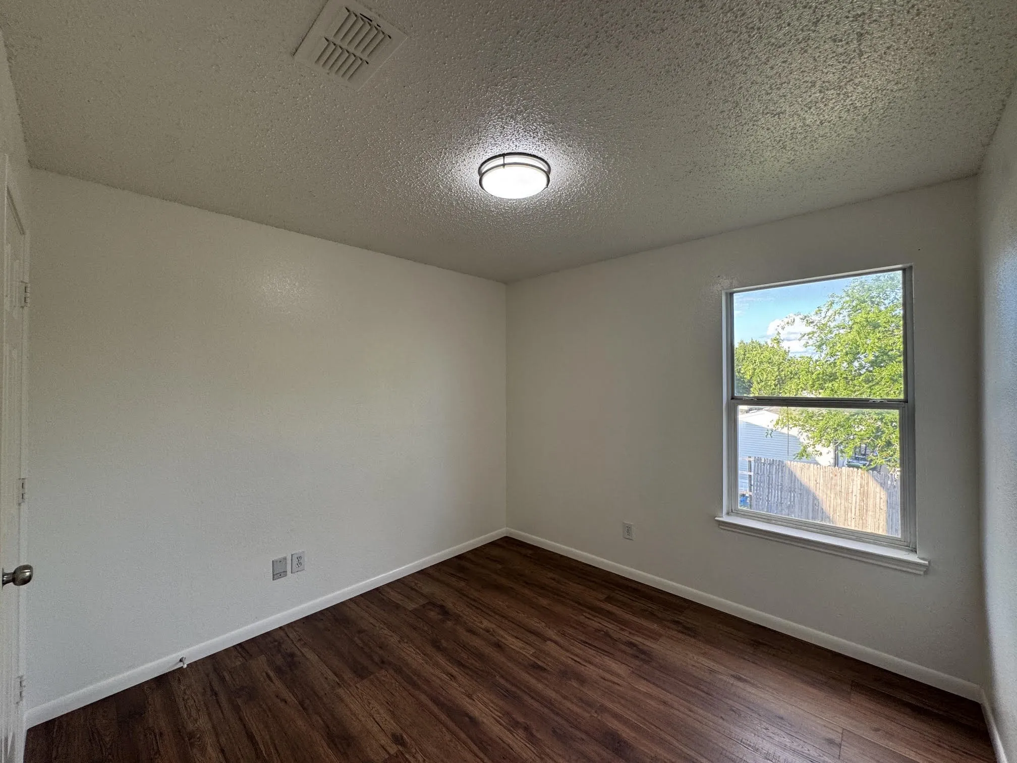 Room featuring wood-finish flooring, white baseboards, and a single window with a white sill