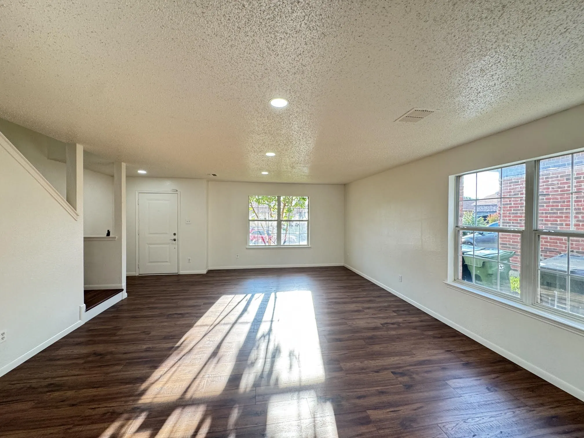 Spacious open-concept room featuring wood-finish flooring, recessed lighting, and multiple windows