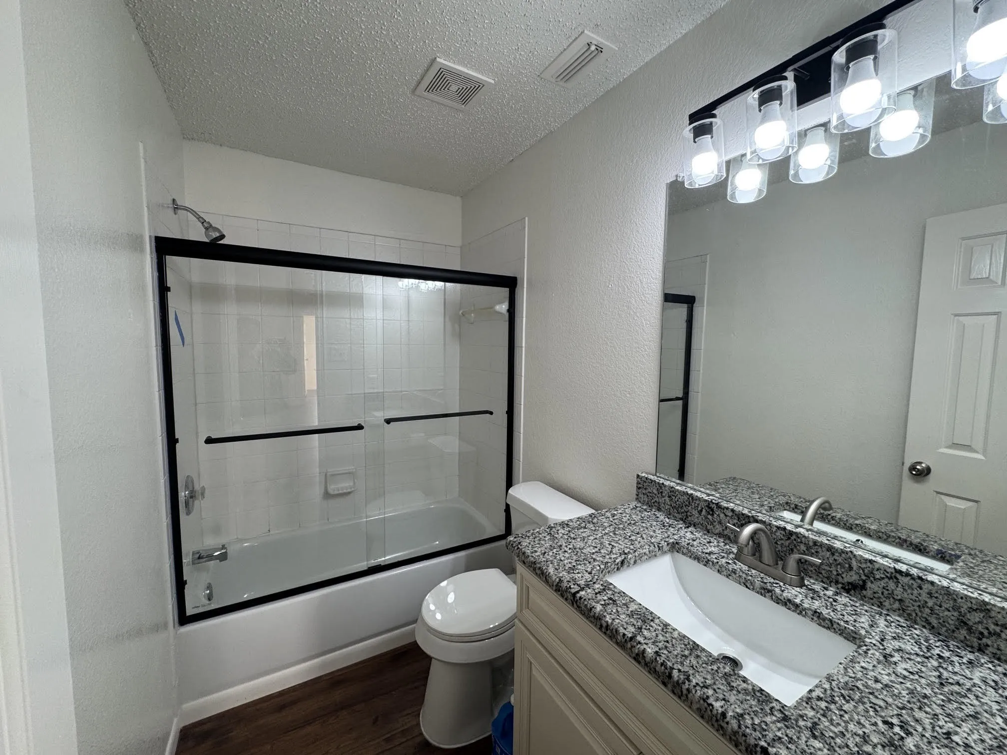 Bathroom featuring a tub/shower combination with black-framed sliding glass doors and white subway tile surround