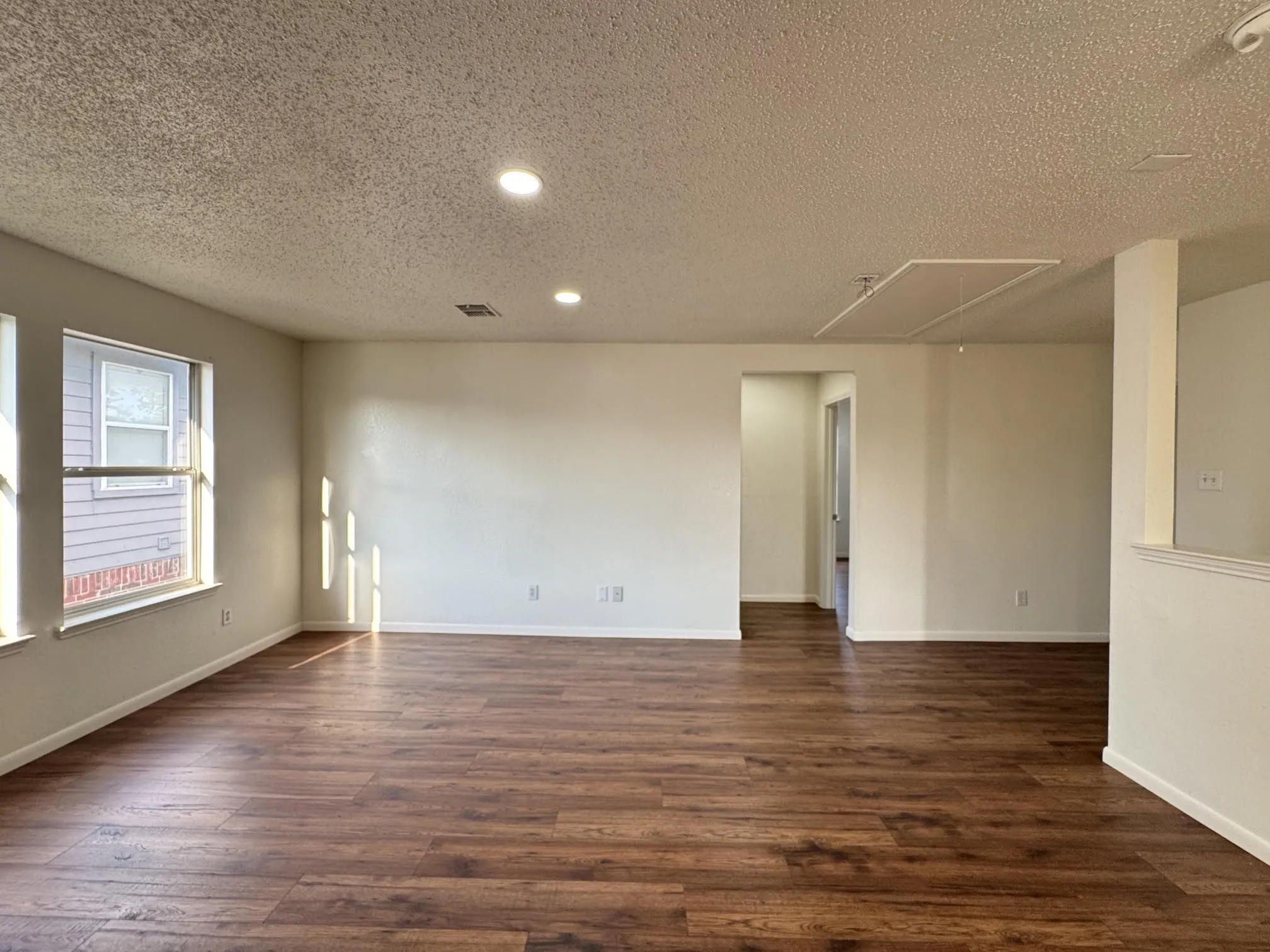 Spacious room featuring wood-finish flooring, recessed lighting, multiple windows, and light-toned walls