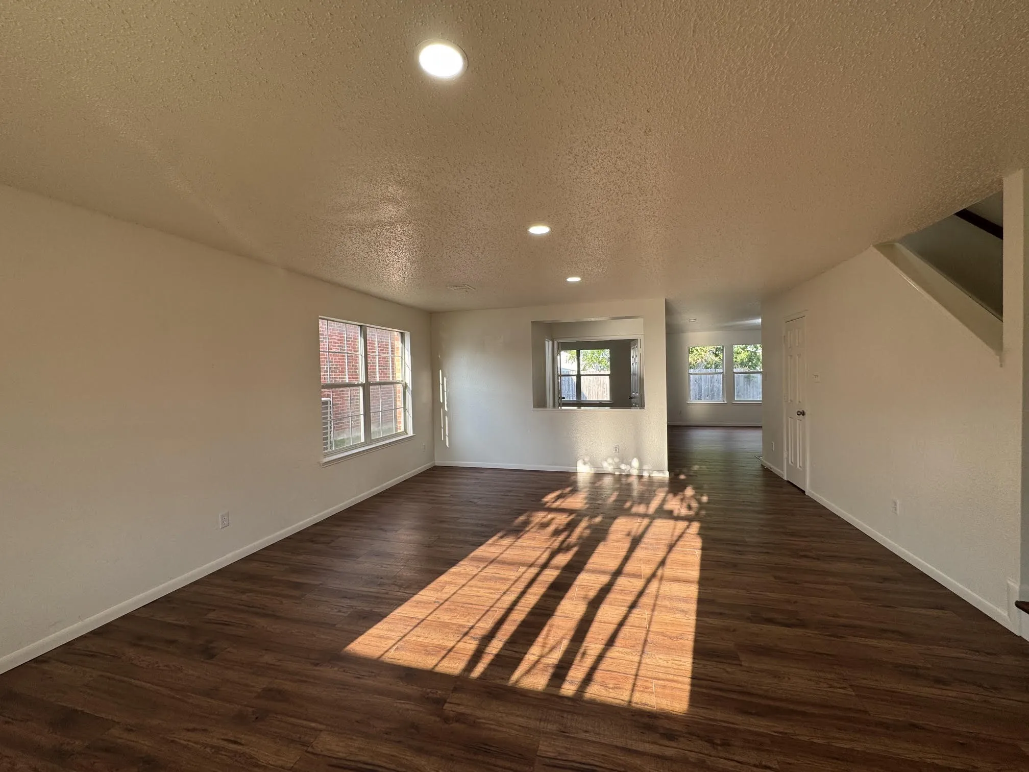 Spacious room with wood-finish flooring, recessed lighting, and multiple windows with blinds